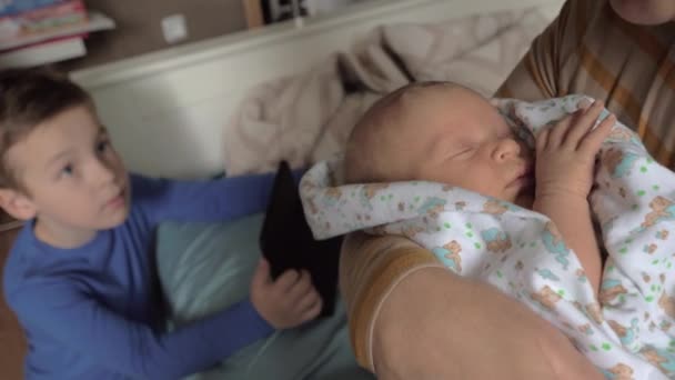Oma mit Enkeln zu Hause. sie schaukelt Baby-Enkelin in den Armen — Stockvideo