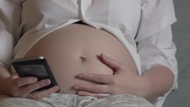 Беременная женщина отдыхает со смартфоном — стоковое видео