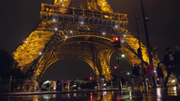 Вид на улицу возле подсвеченной Эйфелевой башни в Париже в ненастную ночь, Франция — стоковое видео