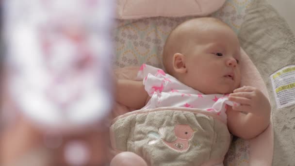 Mother taking mobile photo of baby daughter in bouncy seat — Stock Video