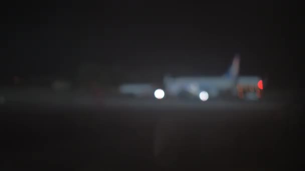 Vista nocturna del tractor de remolque de avión y avión en el aeropuerto, desenfoque — Vídeo de stock