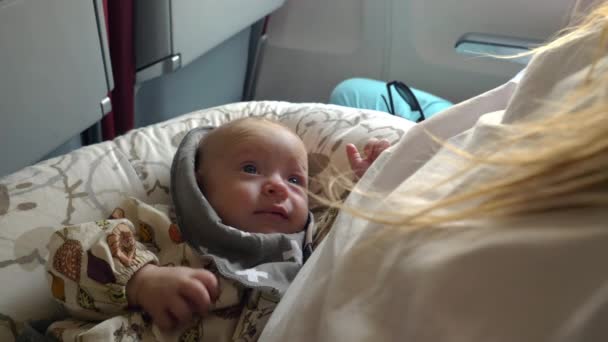 Трехмесячная девочка улыбается и смотрит на маму во время полета — стоковое видео