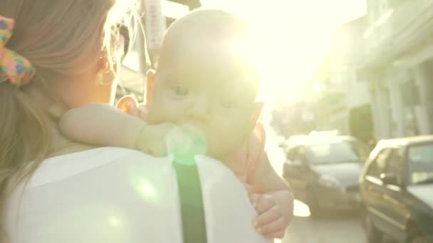 Moeder met baby lopen buiten tegen felle zon flare — Stockvideo