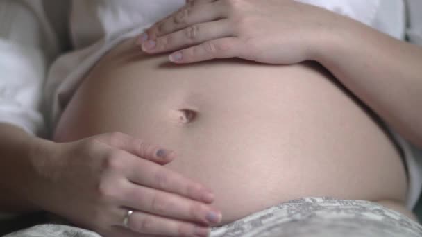 Беременная женщина трогает и гладит живот — стоковое видео