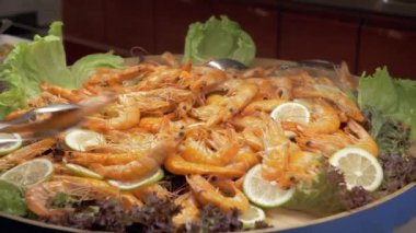 Büyük bir çanak limon ve marul yaprakları ile pişmiş karides tam