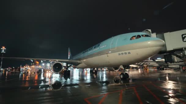 Avião de passageiros da Korean Air com ponte de embarque, vista noturna — Vídeo de Stock