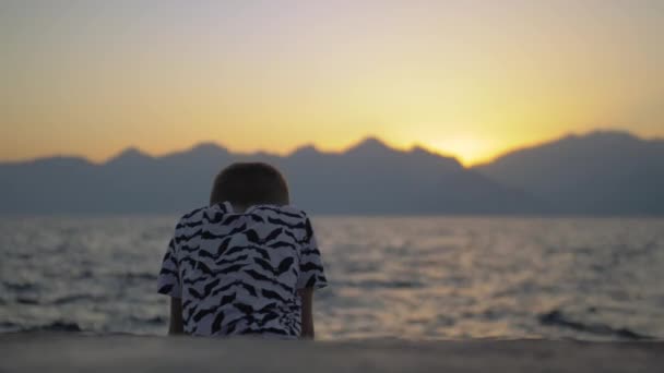 Niño solitario en la playa al atardecer — Vídeo de stock