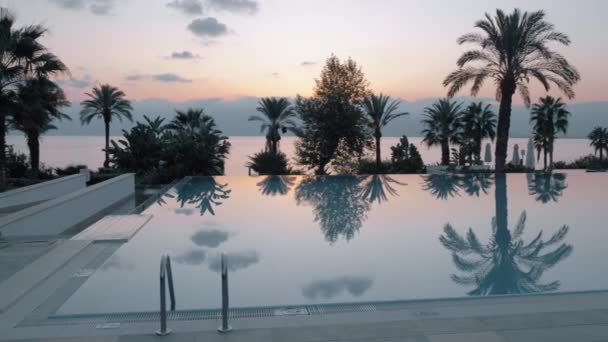 Escena del atardecer del complejo con piscina con vistas al mar y palmeras, Turquía — Vídeo de stock