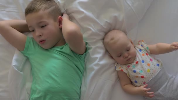 Broer met junior zus op bed thuis — Stockvideo