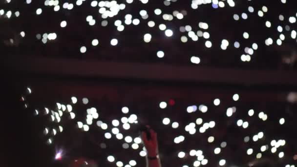 Размытый вид многих ярких экранов смартфонов на концертном шоу — стоковое видео