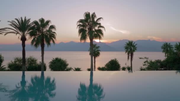 Resort scène met zwembad, de zee en de bergen bij zonsondergang — Stockvideo