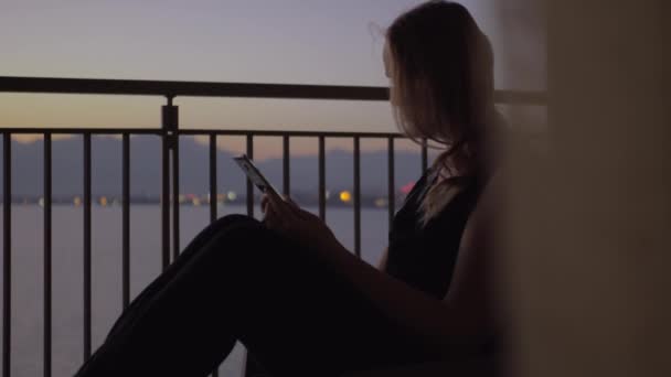 Vrouw met behulp van slimme telefoon op het balkon met uitzicht op zee — Stockvideo