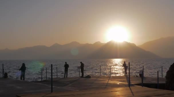 Mannen vissen op de pier bij zonsondergang — Stockvideo