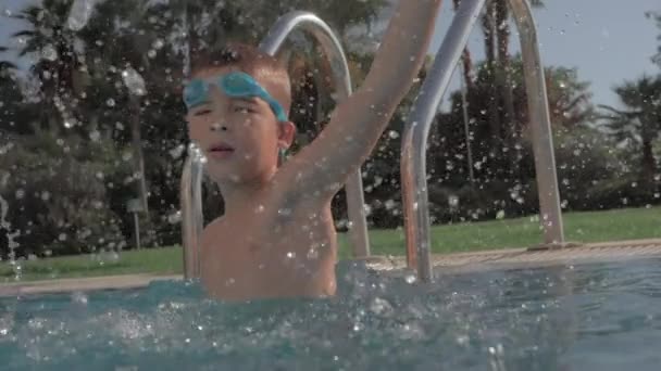 Niño divirtiéndose en la piscina y salpicaduras de agua — Vídeo de stock