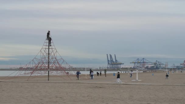 Дети играют на пляже и лазают по канатной сети. Вид на море с помощью кранов, Валенсия — стоковое видео