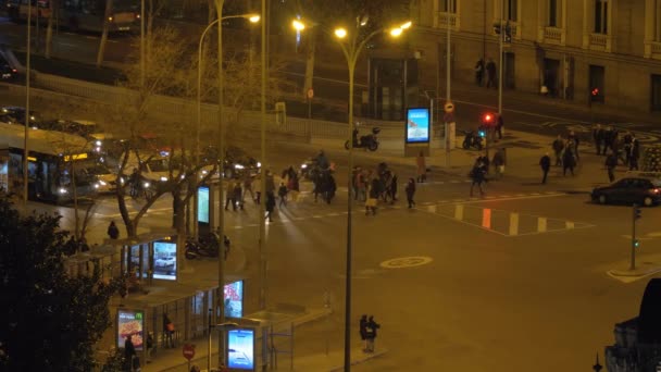 Vue sur la ville en soirée avec les personnes traversant la route et le trafic de transport, Madrid — Video