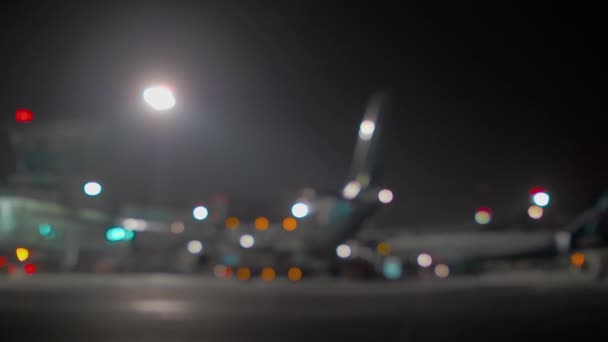 Avião desfocado no terminal do aeroporto à noite — Vídeo de Stock