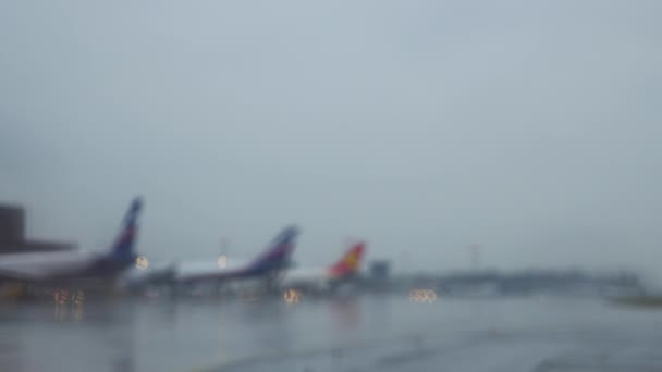Aviones en la terminal sentados en una pista de rodaje mojada — Vídeo de stock