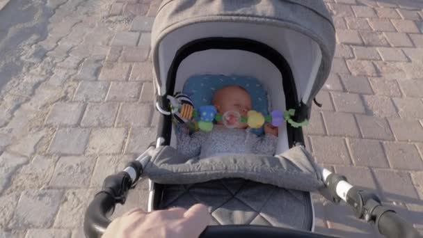 A cute baby girl sleeping in a moving baby carriage — Stock Video