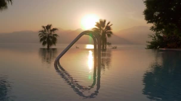 Een steadicam schot van een open zwembad en een zonsondergang aan zee — Stockvideo