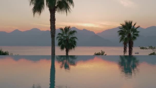Eine Steadicam-Aufnahme eines glänzenden Swimmingpoolrandes und einer abendlichen Meereslandschaft im Hintergrund — Stockvideo
