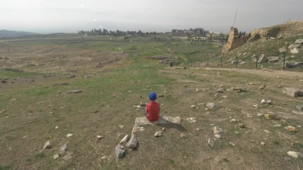 Uno scatto steadicam di un ragazzo che guarda le rovine dell'antica Hierapolis — Video Stock