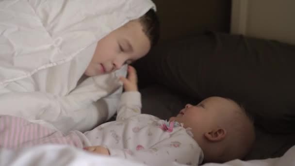 Šťastný chlapec svou malou sestru v posteli — Stock video