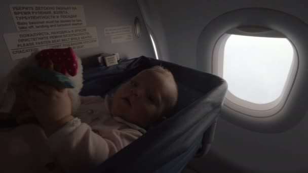 Niña en un moisés en un avión — Vídeo de stock