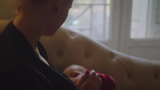 Мать кормит свою дочь грудью у окна — стоковое видео