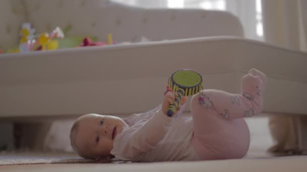 Baby Mädchen in warmen Kleidern spielt auf dem Boden — Stockvideo
