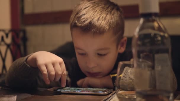 Niño aburrido usando teléfono inteligente en la cafetería — Vídeos de Stock