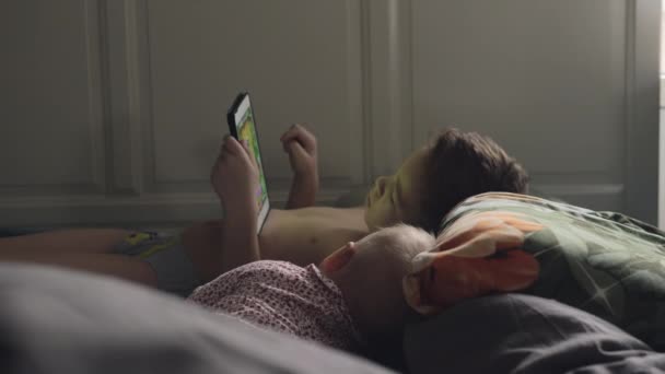 Oudere broer op een tablet met jongere zusje — Stockvideo