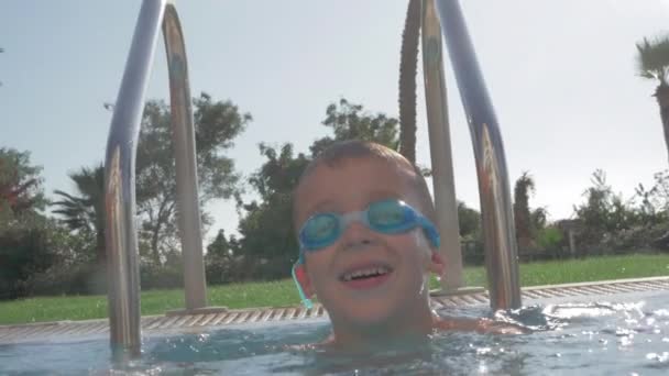 Um movimento lento de um menino feliz em uma piscina aberta — Vídeo de Stock