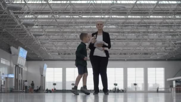 Uma mulher com uma filha bebê e um filho em uma sala de aeroporto — Vídeo de Stock