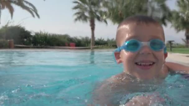 Una cámara lenta de un niño feliz salpicando en una piscina abierta — Vídeo de stock