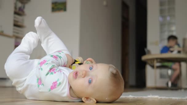 Een meisje van de baby in een kruippakje liggend op de vloer — Stockvideo