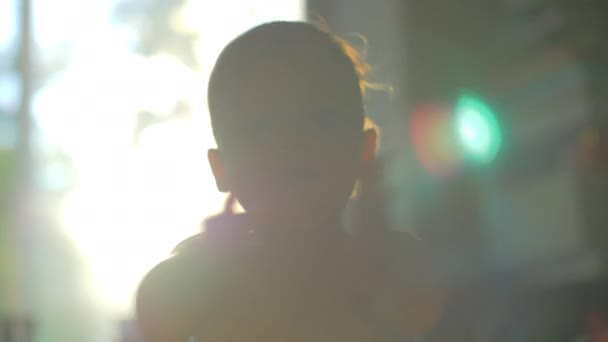 Niño pequeño aplaudiendo de la mano, vista contra la luz del sol en casa — Vídeos de Stock