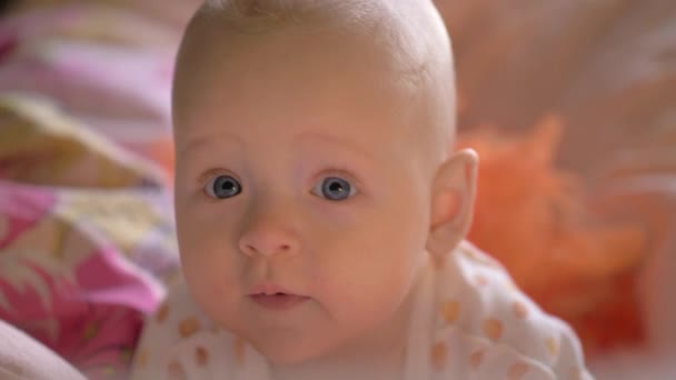 A closeup of a cute baby girl on colorful bed linen — Stock Video
