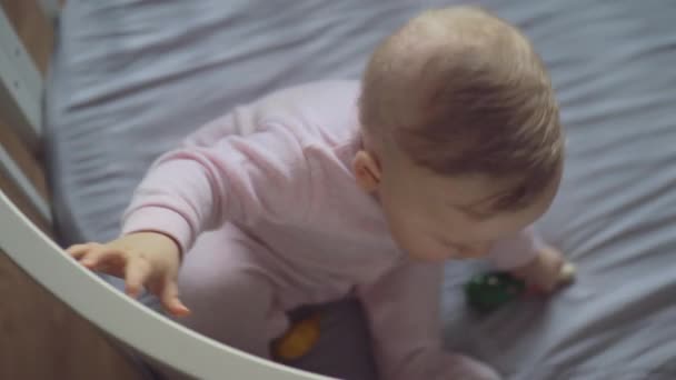 Een bovenaanzicht van een meisje van de baby proberen te komen in een wieg — Stockvideo