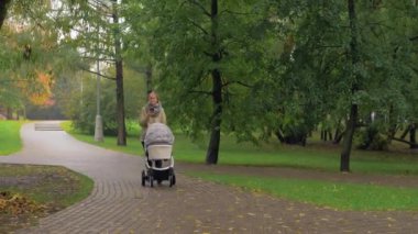 Bebek Sonbahar Park ile yürürken telefon kullanan kadın