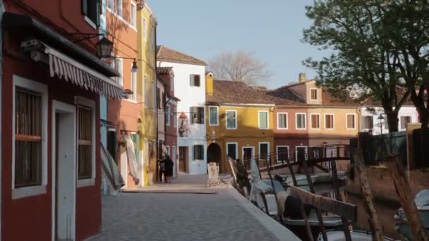 Ярко окрашенные дома на улице с каналом. Бурано, Италия — стоковое видео