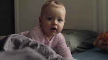 Dağınık yatak pembe romper elbiseli bir kız bebek