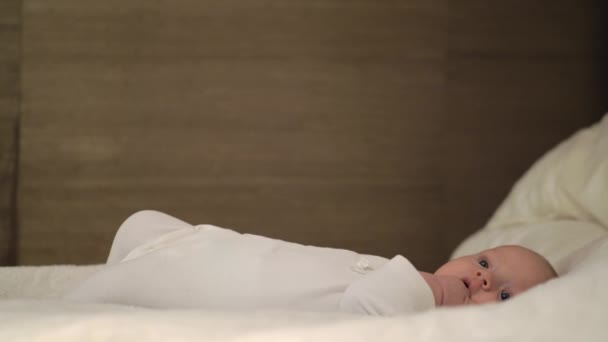 Rustige baby met hand in de mond liggen op grote bed — Stockvideo