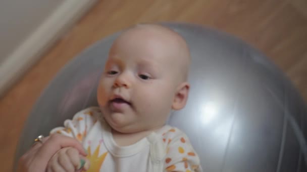 Ein kleines Mädchen liegt auf einem großen silbernen Turnball — Stockvideo