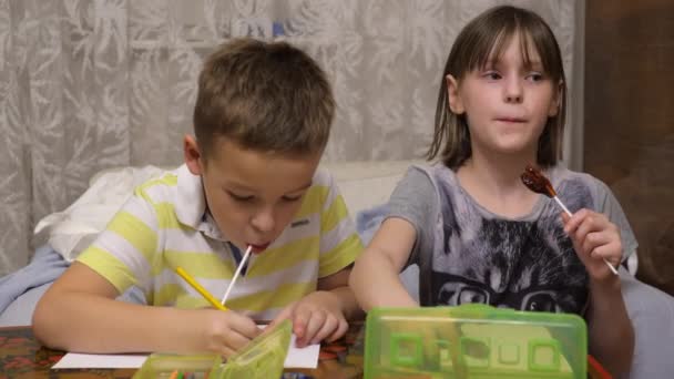 Junge und Mädchen mit Lutschern zeichnen zu Hause mit Buntstiften — Stockvideo