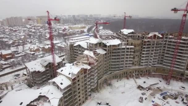 Flying over suburbs of winter city and construction site of apartment complex — Stock Video