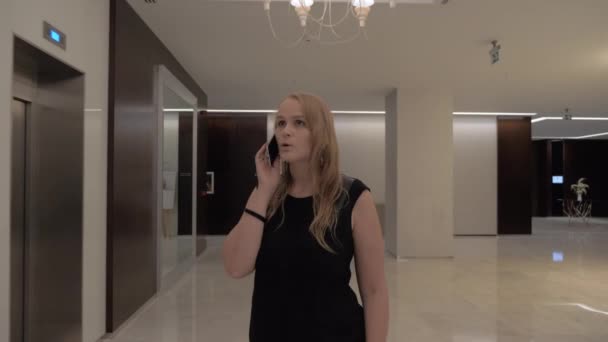 Vrouw praten over de telefoon in de hal van het hotel — Stockvideo