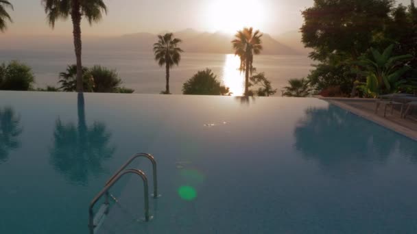 Бассейн на курорте с видом на море и горы, сцена на закате — стоковое видео
