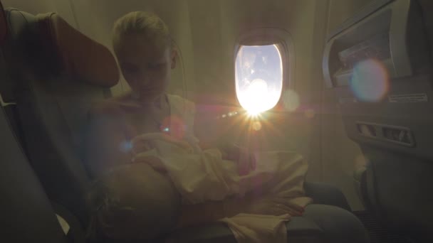 飛行機の中で女性看護赤ちゃんの娘。明るい日差しの中での眺め — ストック動画