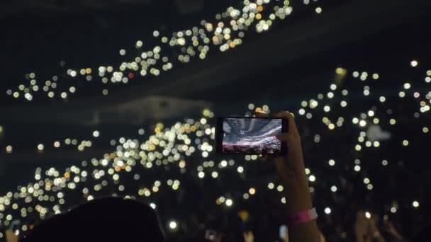 Público con luces en sala de conciertos y mujer tomando vídeo móvil — Vídeo de stock